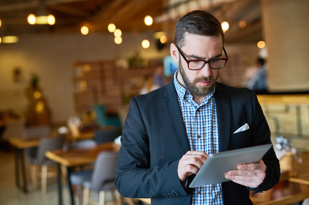 Business owner reviewing a company mobile app on a tablet